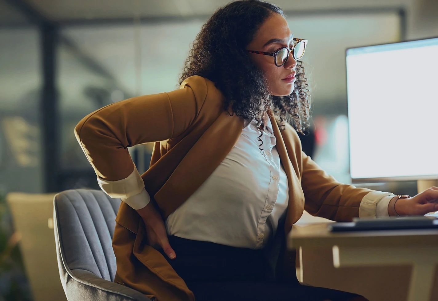 A professional woman in business attire and glasses looking at a computer screen. A professional woman in business attire and glasses looking at a computer screen.
