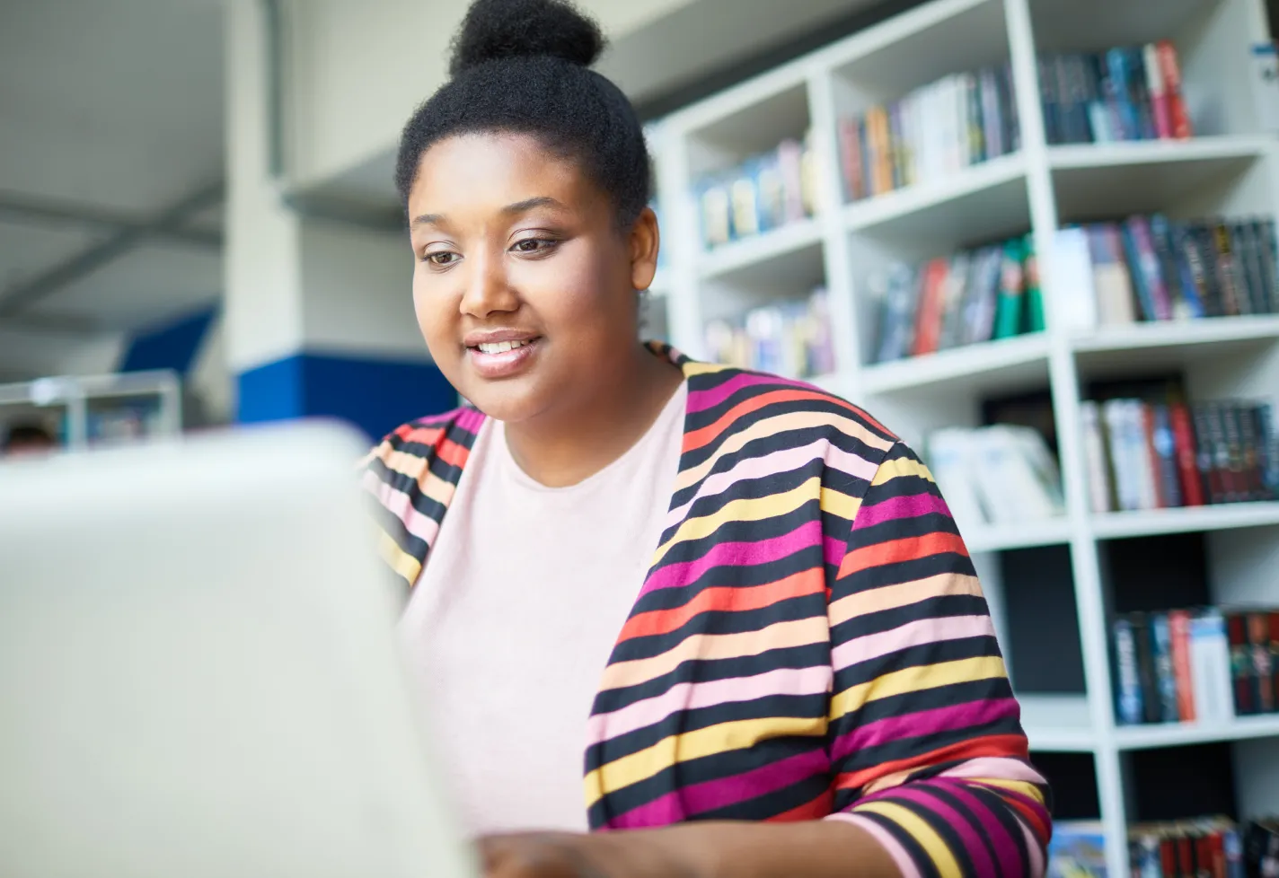 A woman is sitting in her home office typing on her laptop. 