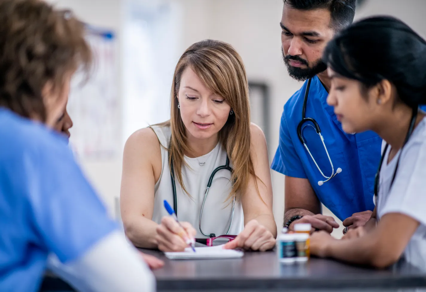 A group of residents are gathered around their preceptor as they listen and discuss. 