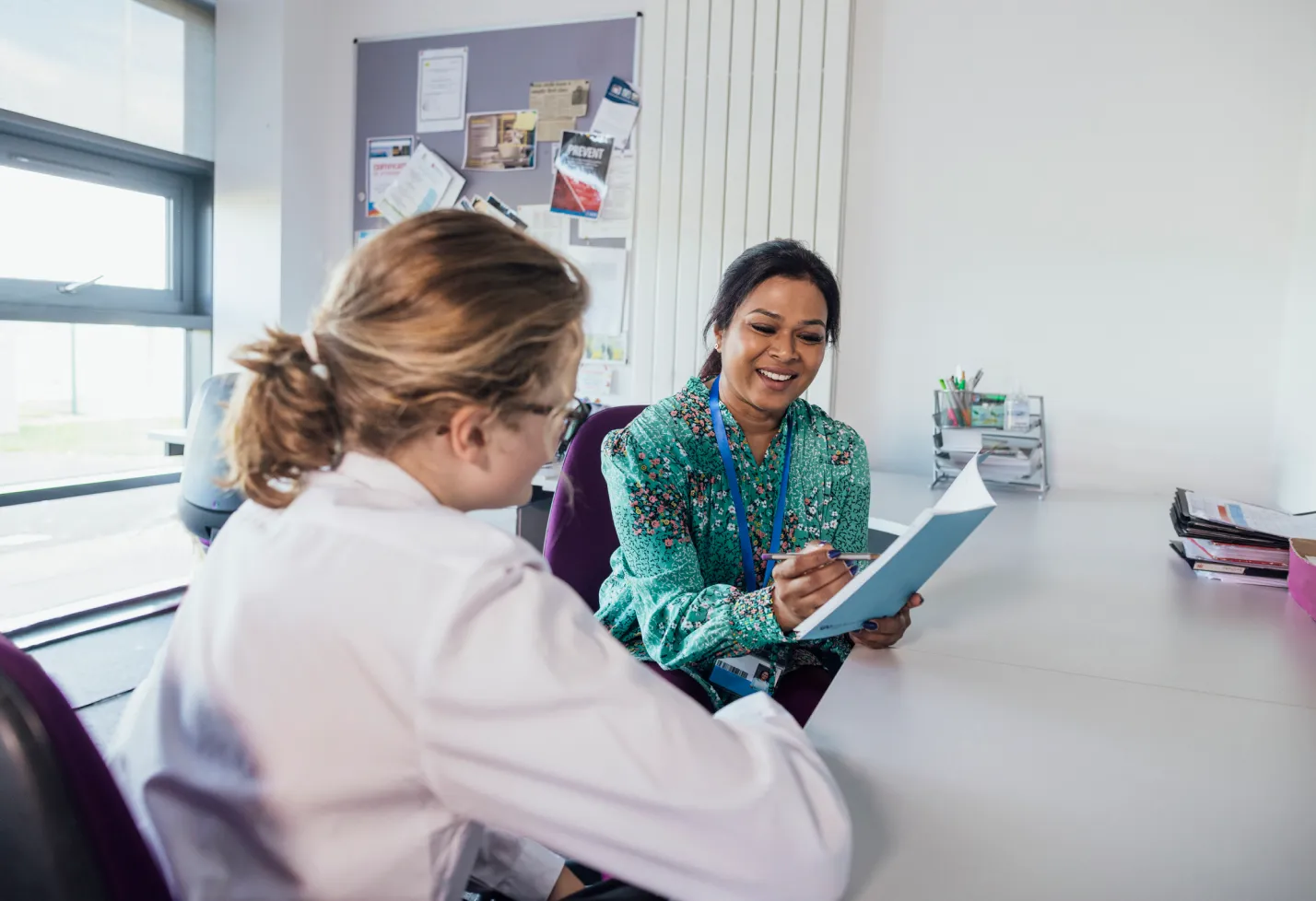 A resident is sitting in an office with an instructor discussing material. A resident is sitting in an office with an instructor discussing material.
