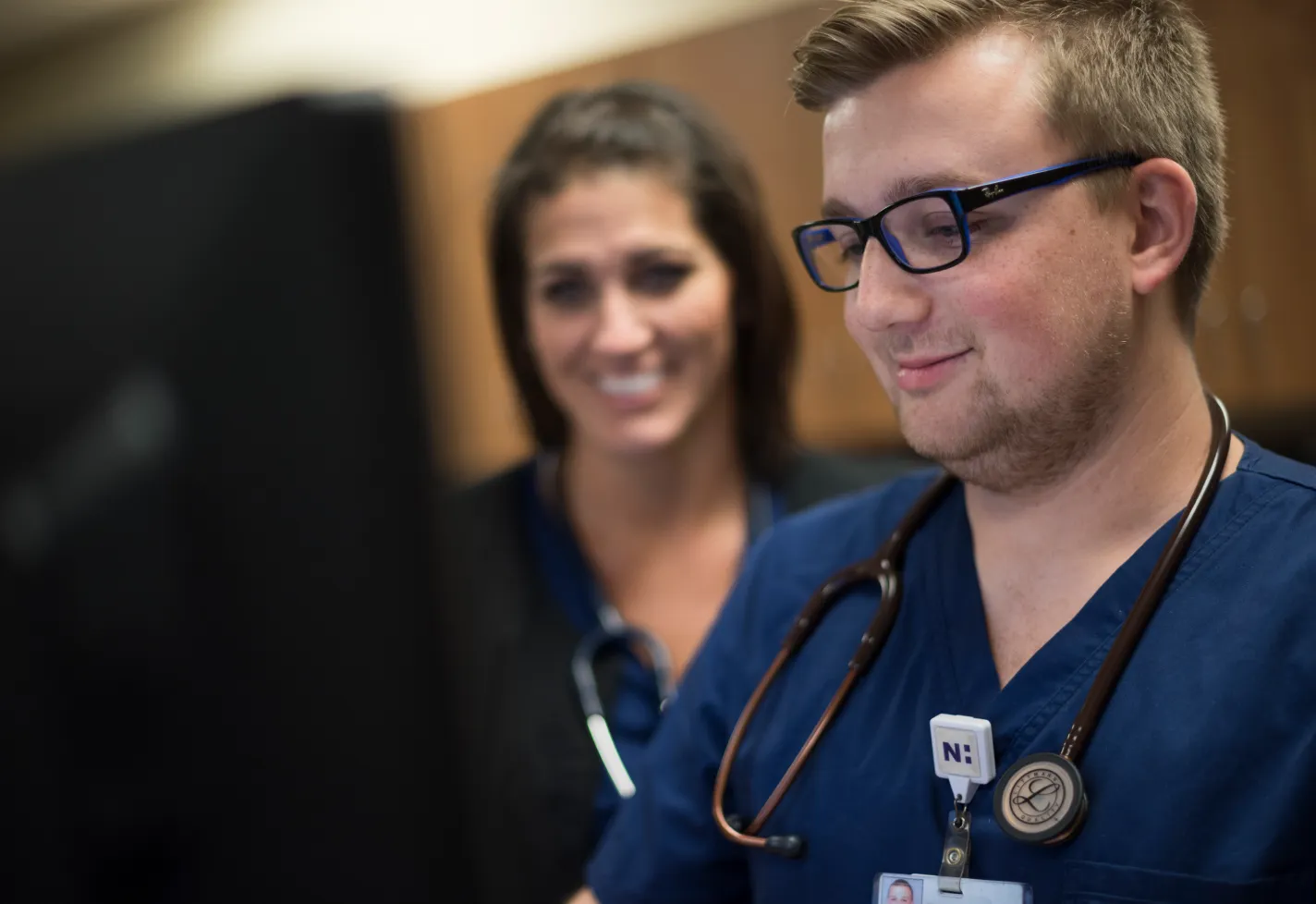 Close up of two nurses sitting at a desk review information on a computer