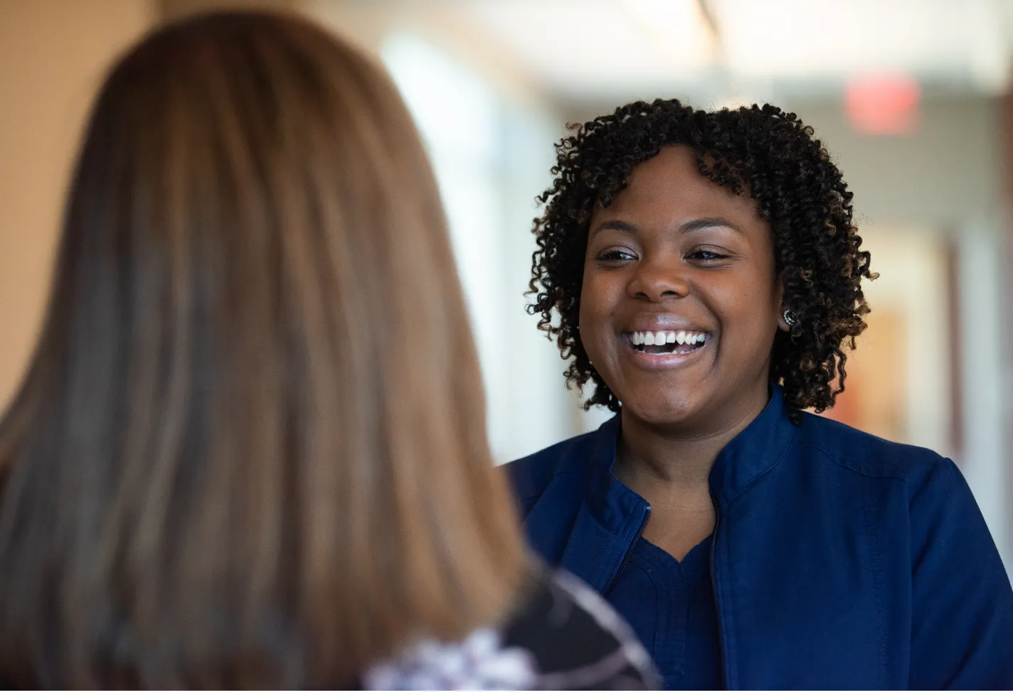 Two registered nurses are talking and laughing with each other. 