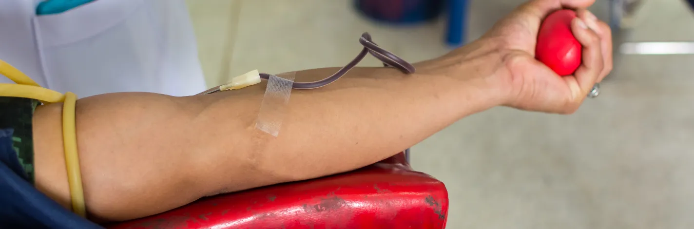 Photo of a patient squeezing a red ball while having blood drawn