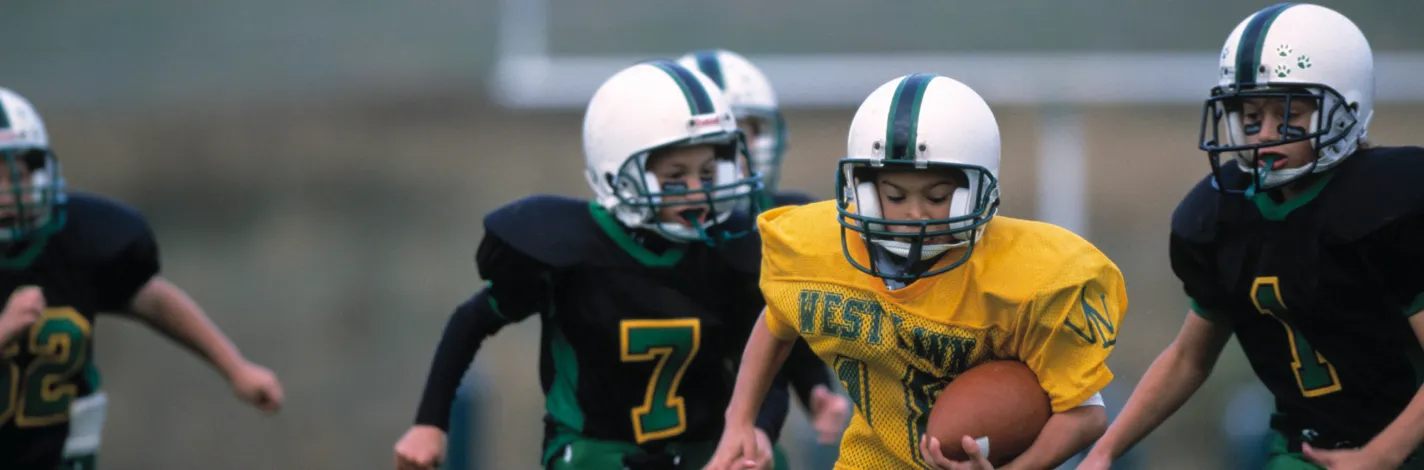 Photo of boys in helmets and uniforms playing football