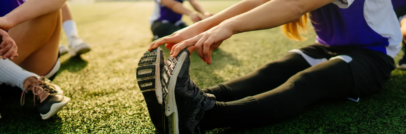 Girls athletic team stretching outdoors.