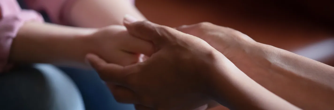 Two people sitting face to face, showing hands supporting a patient