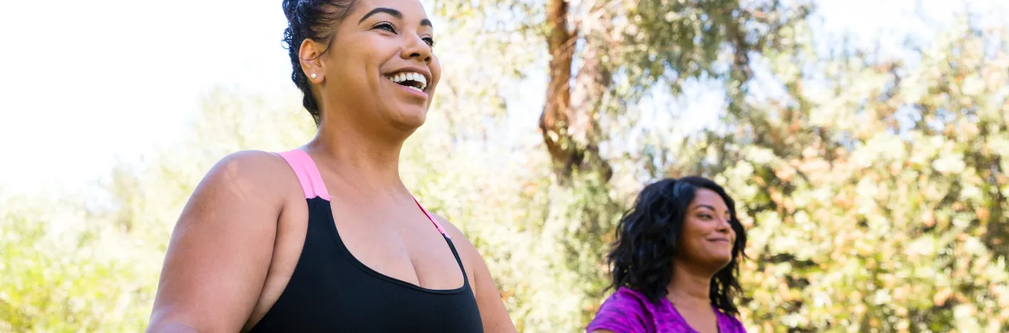 Two women dressed in athletic gear doing yoga outside 