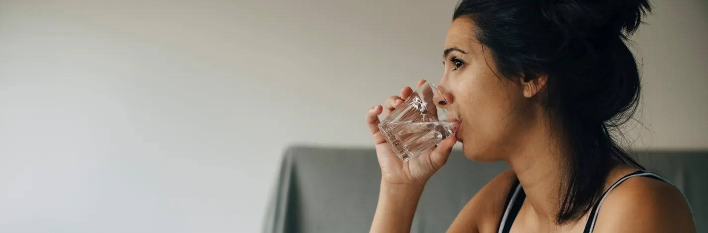 woman in bed taking medication and drinking water