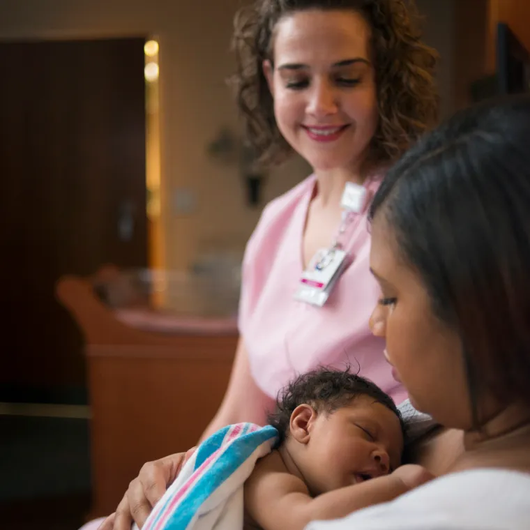 Lactation consultant teaching new mother how to breastfeed newborn baby