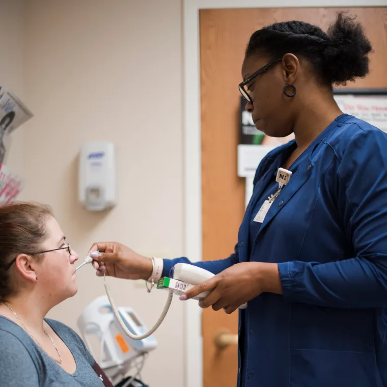 A nurse takes a women's temperature