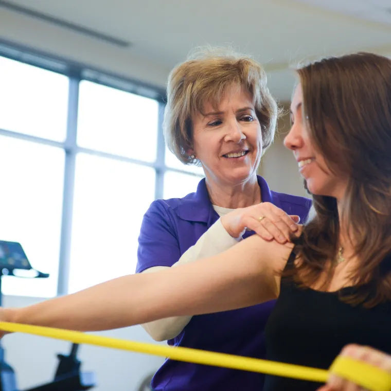 A physical therapist is guiding a woman as she completes exercises. A physical therapist is guiding a woman as she completes exercises.