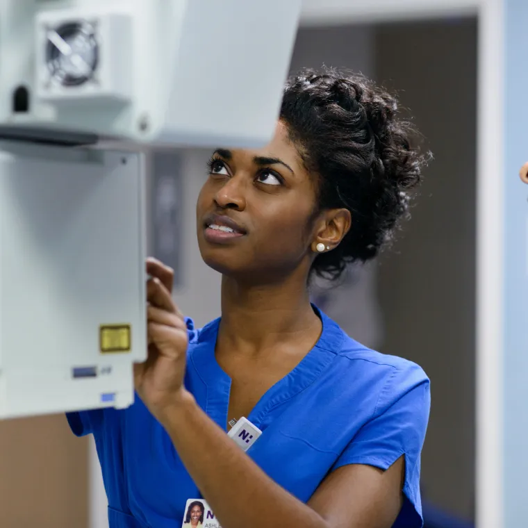 A Novant Health team member is operating a machine to capture an patients imaging scan. 