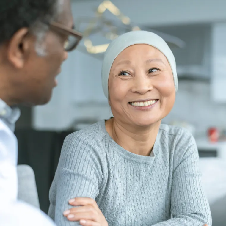 A cancer patient is sitting, smiling, and talking with her healthcare provider. A cancer patient is sitting, smiling, and talking with her healthcare provider.