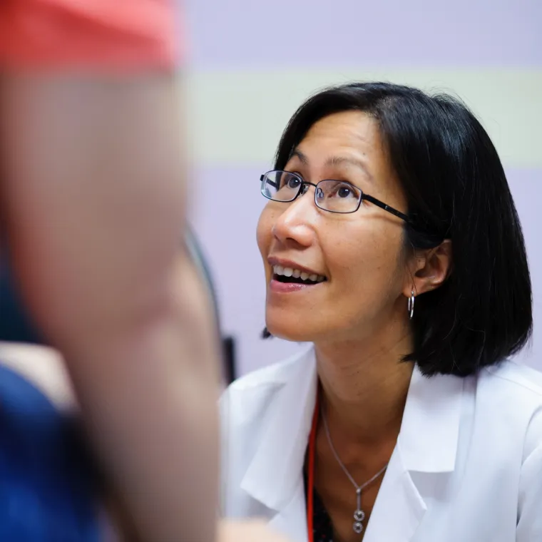 Woman provider looking up smiling as she exams a patient. 