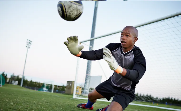 Soccer goalkeeper trying to catch a soccer ball.