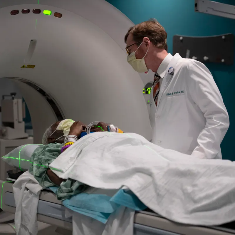 Dr. Warlick is talking with a patient as they prepare for a scan. Dr. Warlick is talking with a patient as they prepare for a scan.