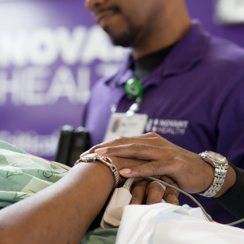 A Novant Health team member is holding the hand of an emergency trauma patient as they transport them. A Novant Health team member is holding the hand of an emergency trauma patient as they transport them.