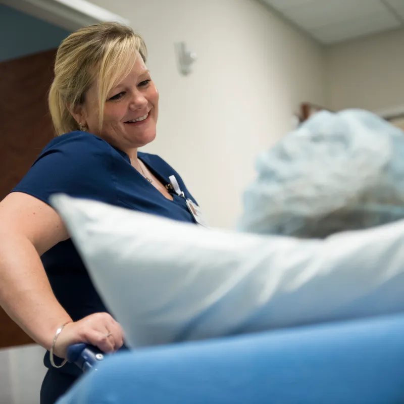 Nurse smiling at patient as she wheels them towards the operating room. 