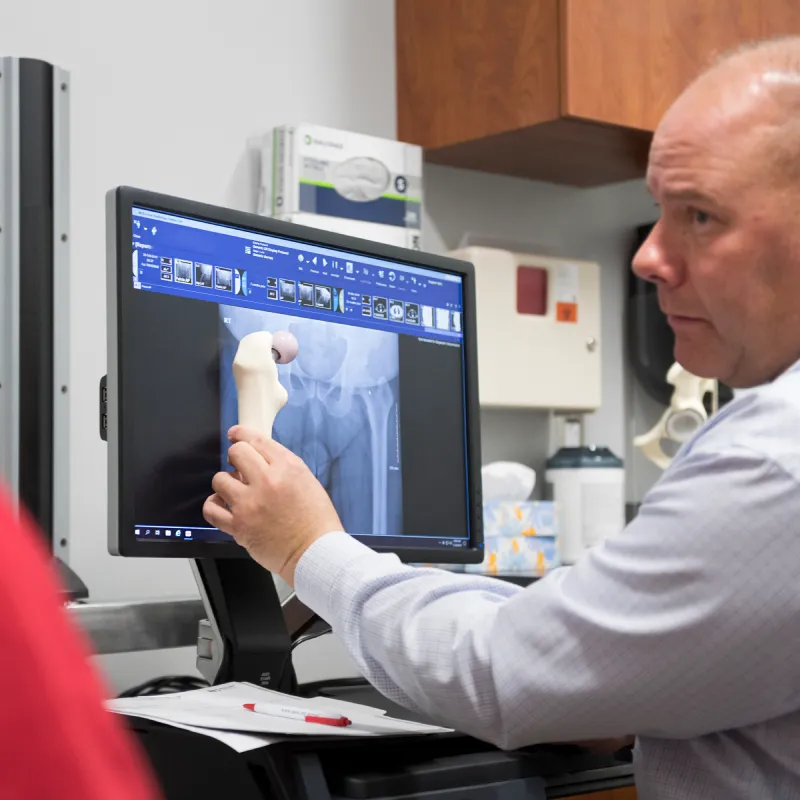 Dr. Crave is holding up a bone next to a patients x-ray to demonstrate care Dr. Crave is holding up a bone next to a patients x-ray to demonstrate care