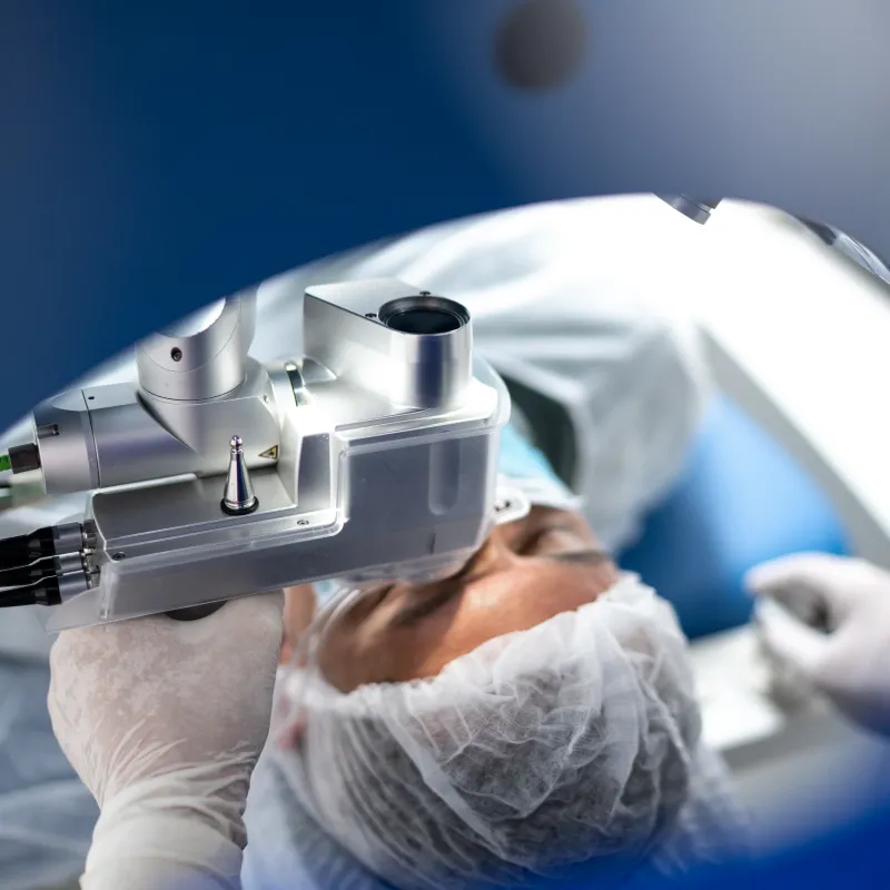 A healthcare provider is positioning a machine over a patient's eye during eye surgery. A healthcare provider is positioning a machine over a patient's eye during eye surgery.