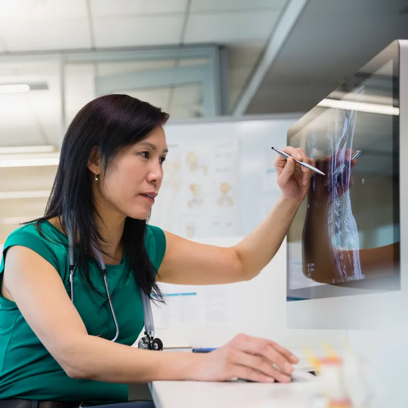 A healthcare provider is reviewing a patients imaging scans on a desktop computer. 