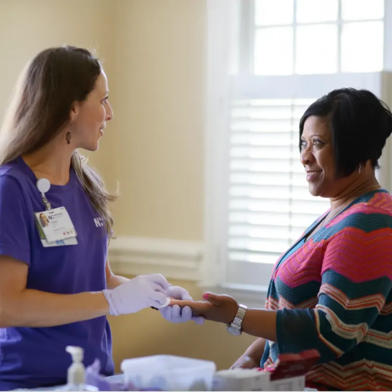 Novant Health registered nurse is preparing a patients for a finger prick screening.